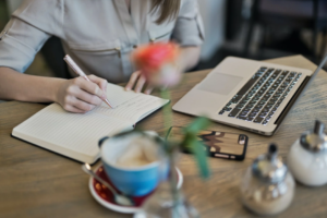 writing in a notebook with laptop